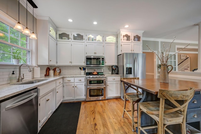kitchen with a sink, light stone counters, white cabinets, and stainless steel appliances