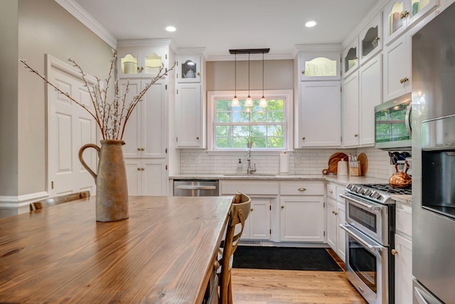 kitchen featuring white cabinets, stainless steel appliances, ornamental molding, and a sink