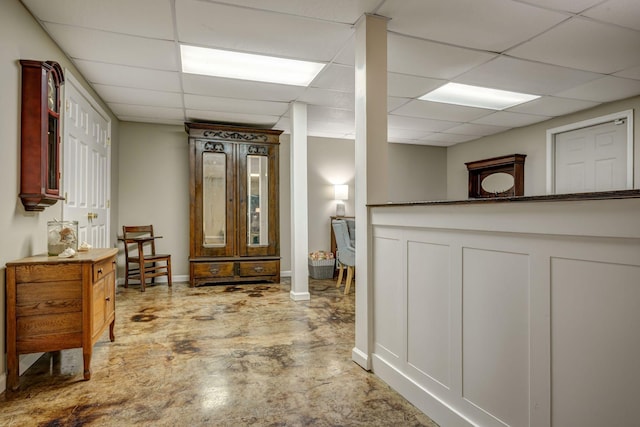 hall with a paneled ceiling and unfinished concrete floors