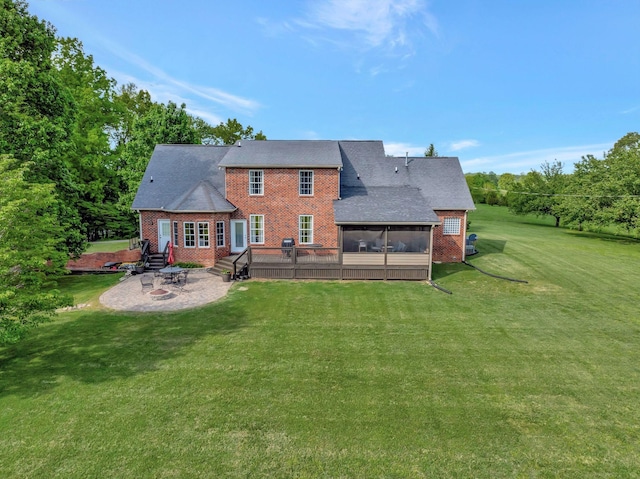 back of house featuring brick siding, a lawn, a sunroom, and a patio