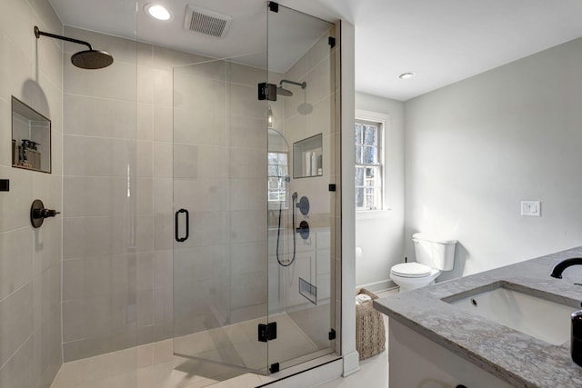 bathroom featuring toilet, visible vents, a shower stall, and vanity