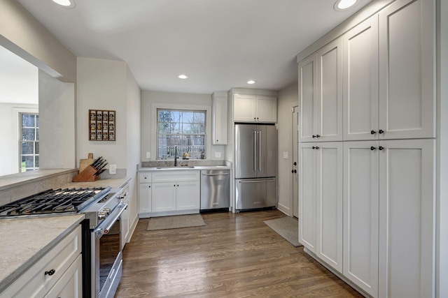 kitchen featuring wood finished floors, recessed lighting, light countertops, white cabinetry, and premium appliances
