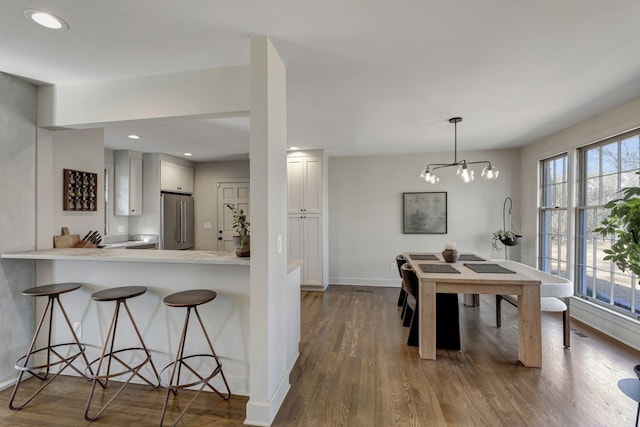 kitchen featuring dark wood finished floors, baseboards, a breakfast bar, and high quality fridge