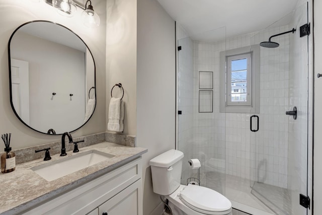 bathroom featuring vanity, a shower stall, and toilet