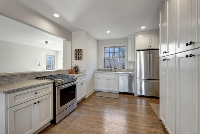 kitchen featuring appliances with stainless steel finishes, white cabinetry, recessed lighting, a peninsula, and wood finished floors