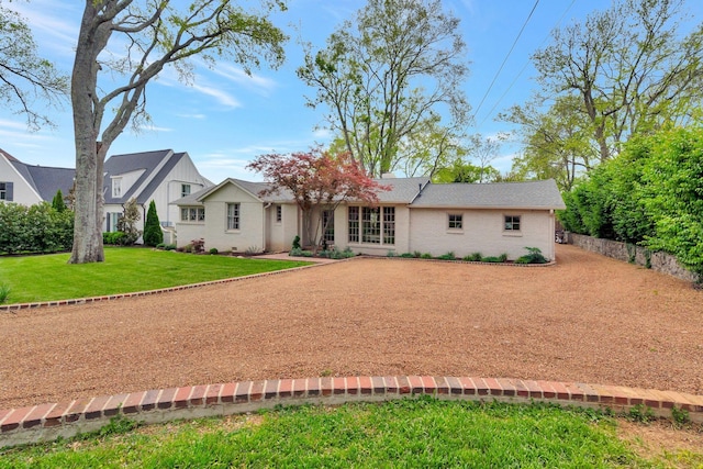 ranch-style house featuring driveway, brick siding, and a front yard