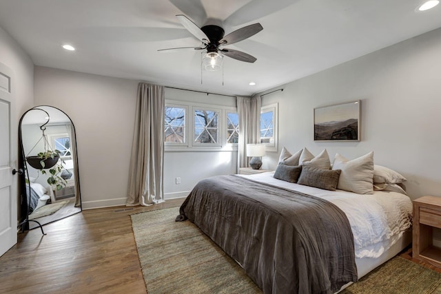 bedroom with recessed lighting, baseboards, wood finished floors, and multiple windows