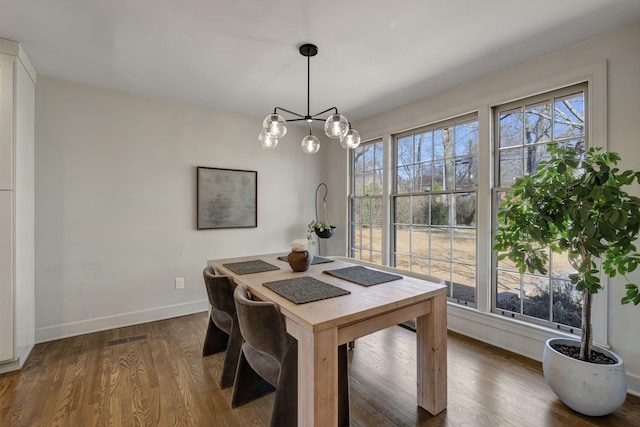 dining room featuring baseboards, a notable chandelier, wood finished floors, and visible vents