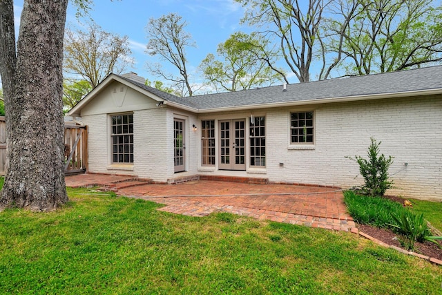 back of property featuring roof with shingles, french doors, brick siding, a patio area, and a yard