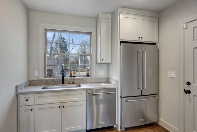 kitchen featuring a sink, light countertops, stainless steel appliances, and white cabinetry