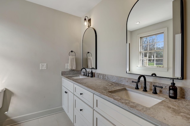 full bathroom with baseboards, double vanity, tile patterned floors, and a sink