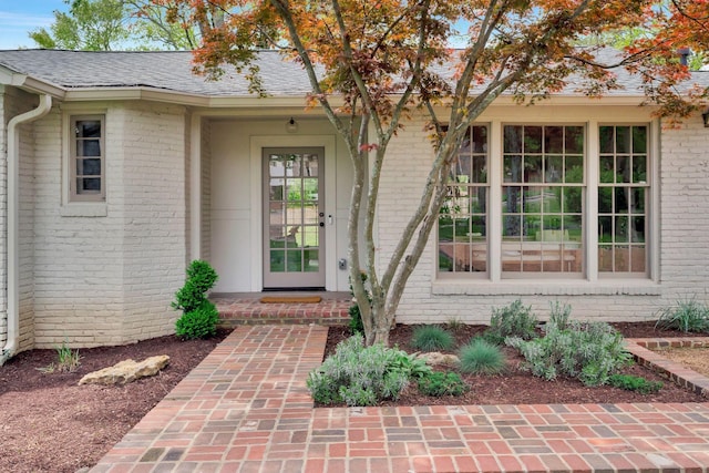 property entrance with brick siding and roof with shingles