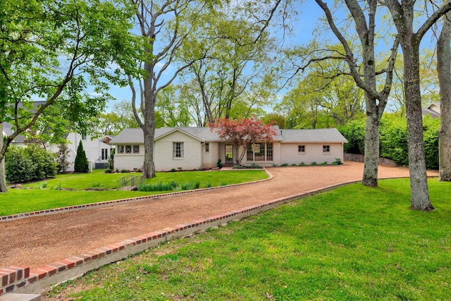 rear view of property with a lawn and driveway