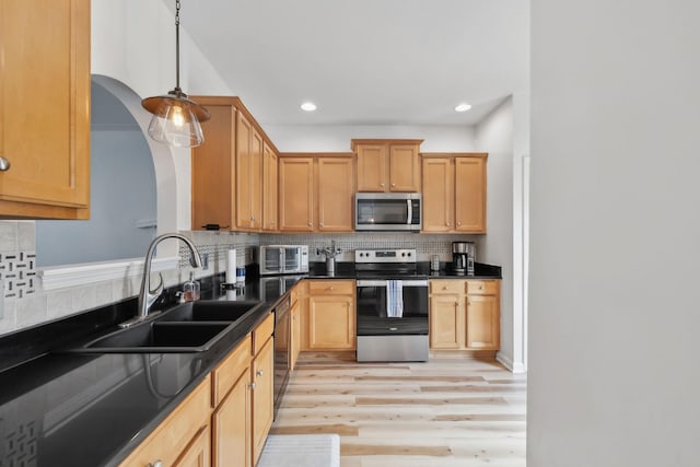 kitchen featuring backsplash, stainless steel appliances, dark countertops, and a sink