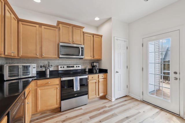 kitchen with dark countertops, light wood-style floors, recessed lighting, tasteful backsplash, and appliances with stainless steel finishes