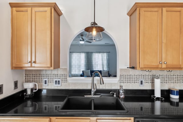 kitchen with a sink, dark countertops, ceiling fan, and tasteful backsplash