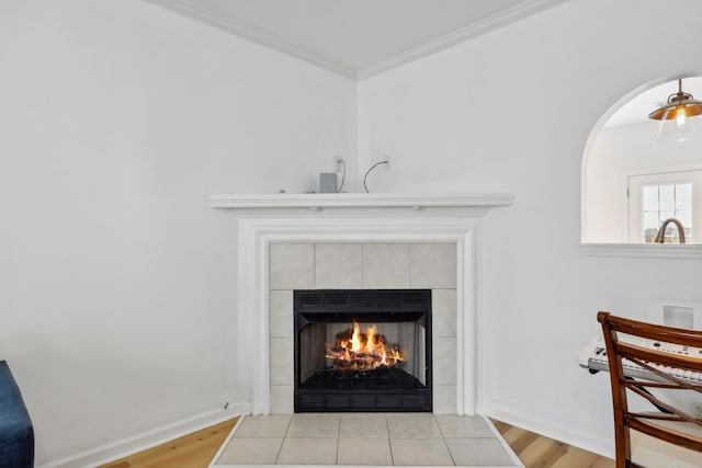 room details featuring crown molding, baseboards, a tile fireplace, and wood finished floors