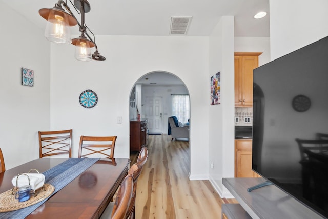 dining room featuring arched walkways, visible vents, and light wood-style flooring