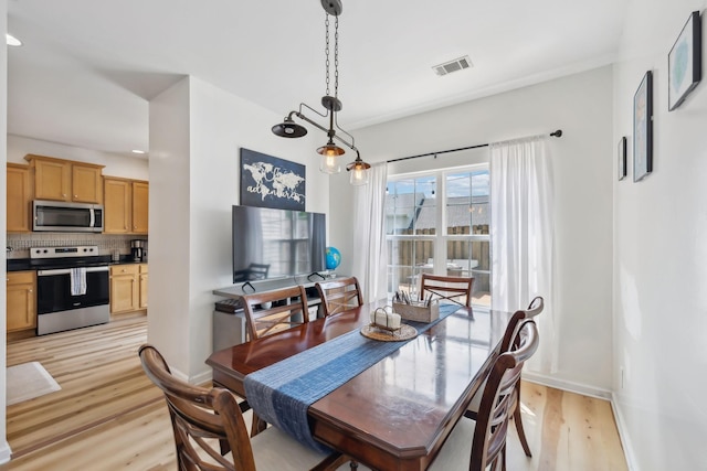 dining space with visible vents, light wood-style floors, and baseboards