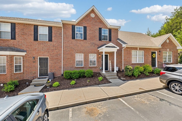 multi unit property featuring brick siding and uncovered parking
