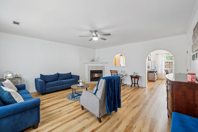 living area with a ceiling fan, visible vents, light wood-style flooring, and a fireplace