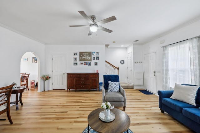 living room with arched walkways, ornamental molding, stairs, and light wood-style flooring