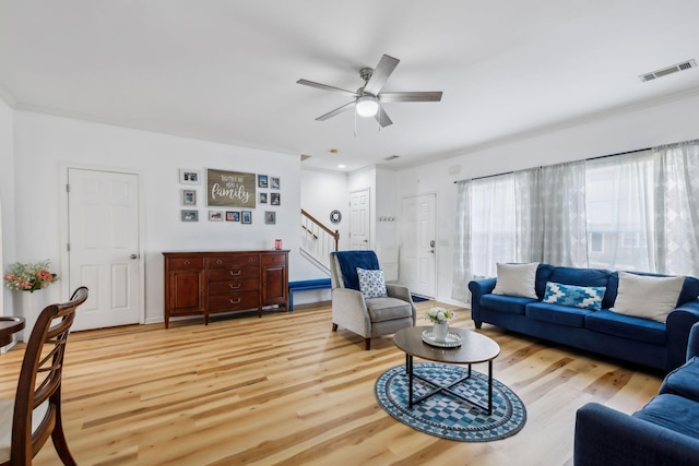 living room featuring visible vents, stairs, ceiling fan, and light wood-type flooring