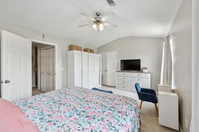 bedroom with visible vents, multiple closets, lofted ceiling, and light carpet
