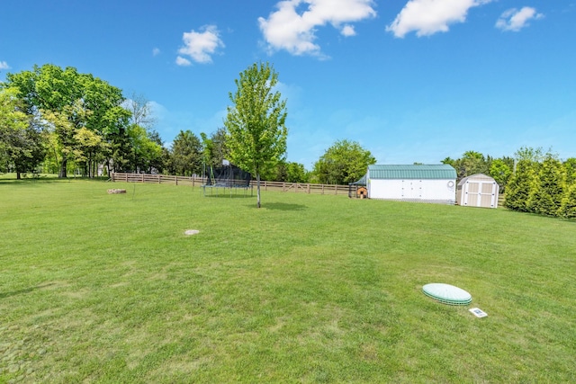 view of yard featuring fence, an outdoor structure, and a storage unit
