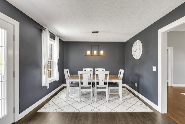 dining room featuring baseboards, a textured ceiling, wood finished floors, and a notable chandelier