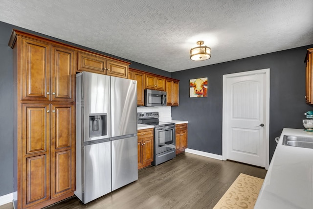 kitchen featuring appliances with stainless steel finishes, brown cabinets, light countertops, baseboards, and dark wood-type flooring