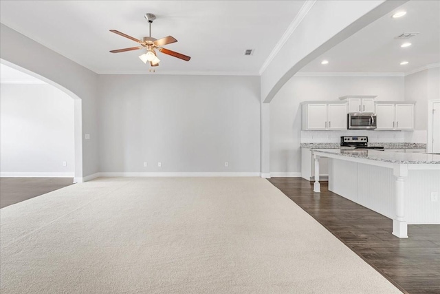 unfurnished living room with visible vents, arched walkways, ceiling fan, and ornamental molding