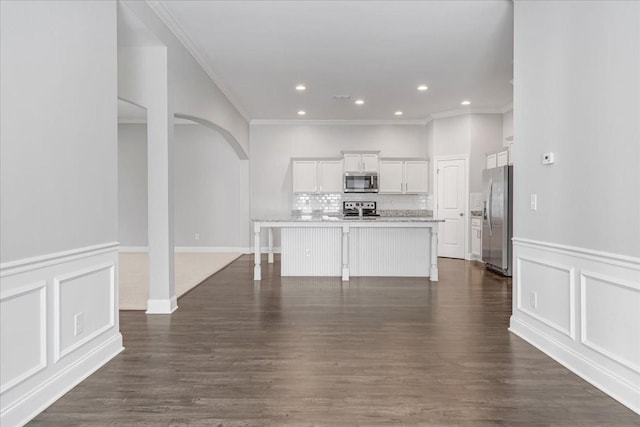 unfurnished living room featuring arched walkways, ornamental molding, and dark wood-type flooring