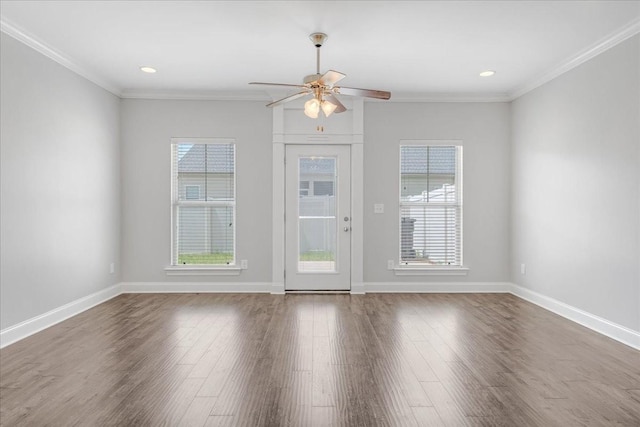 spare room with plenty of natural light, ornamental molding, a ceiling fan, and wood finished floors