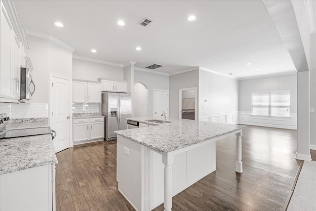kitchen with appliances with stainless steel finishes, a sink, arched walkways, a large island with sink, and ornamental molding
