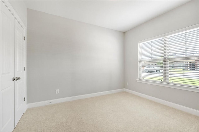 spare room featuring baseboards and light colored carpet