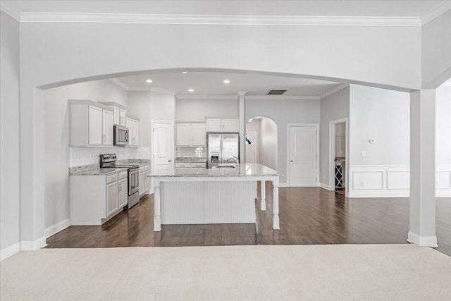 kitchen featuring appliances with stainless steel finishes, dark wood-style floors, light stone counters, and visible vents