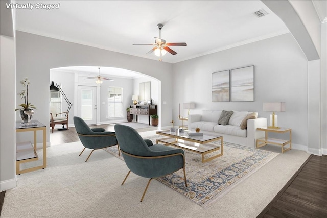 living area with arched walkways, ceiling fan, wood finished floors, and visible vents