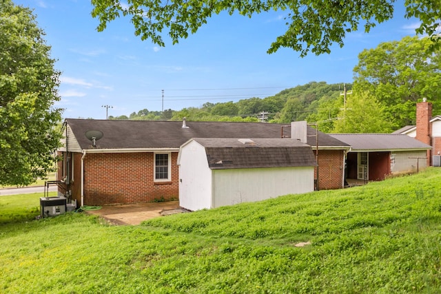 702 1st Ave, Mount Pleasant, TN 38474 - back of house featuring brick siding, a storage shed, a lawn, and an outbuilding