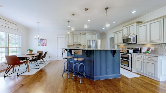kitchen with decorative backsplash, a breakfast bar area, light stone countertops, light wood finished floors, and stainless steel appliances