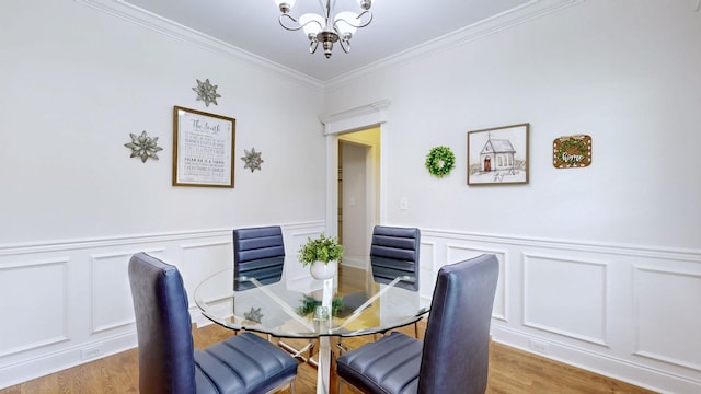dining space featuring a notable chandelier, light wood finished floors, and a decorative wall