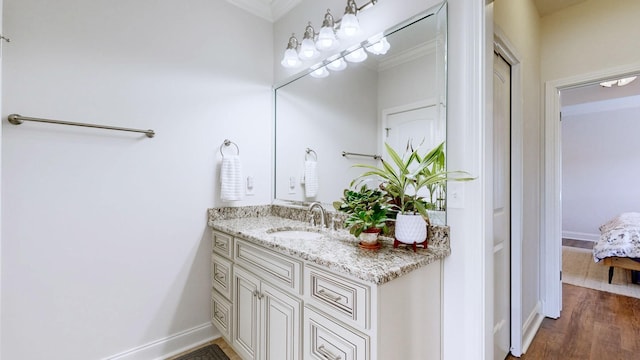 bathroom featuring vanity, baseboards, ornamental molding, and wood finished floors