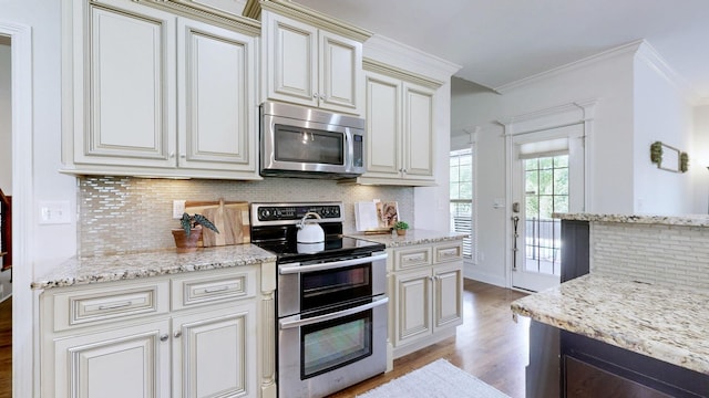 kitchen with decorative backsplash, light stone countertops, stainless steel appliances, and light wood finished floors