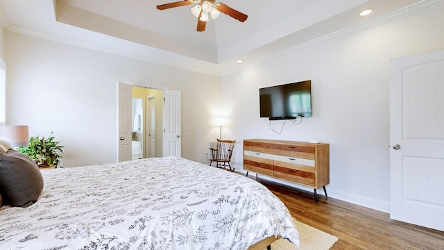 bedroom featuring crown molding, wood finished floors, baseboards, a tray ceiling, and recessed lighting