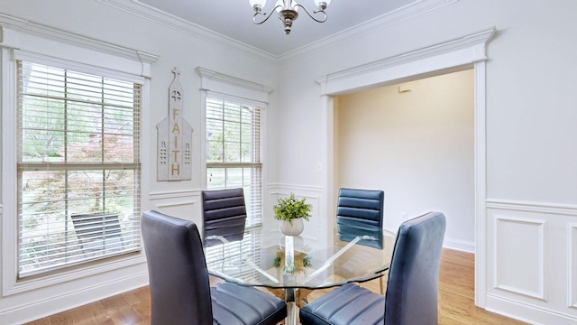 dining room featuring ornamental molding, wainscoting, wood finished floors, and a chandelier