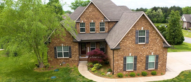 view of front of property featuring brick siding, a shingled roof, and a front lawn