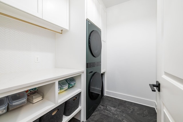 743 Fontwell Ln, Franklin, TN 37064 - laundry room with cabinet space, baseboards, stone finish floor, and stacked washer and clothes dryer