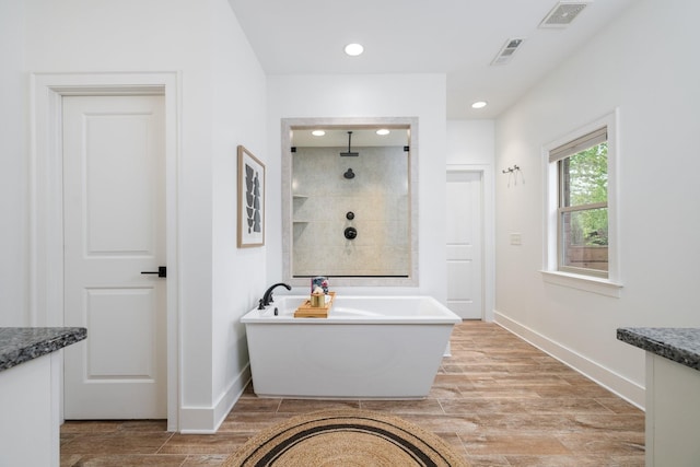 743 Fontwell Ln, Franklin, TN 37064 - bathroom with visible vents, a freestanding bath, wood finished floors, and tiled shower
