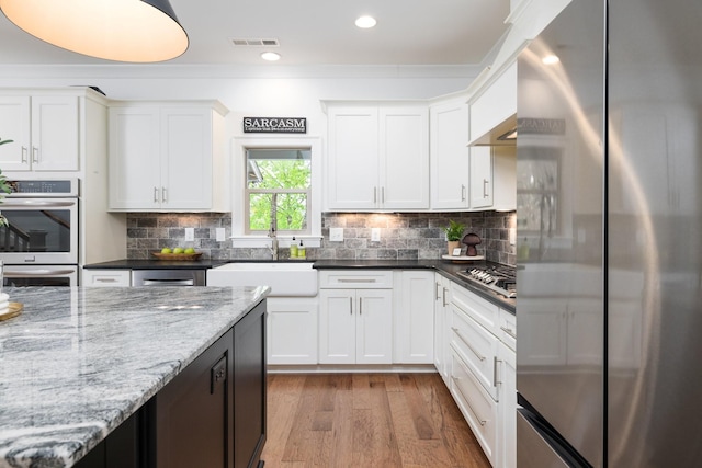 743 Fontwell Ln, Franklin, TN 37064 - kitchen featuring visible vents, wood finished floors, white cabinets, a sink, and stainless steel appliances