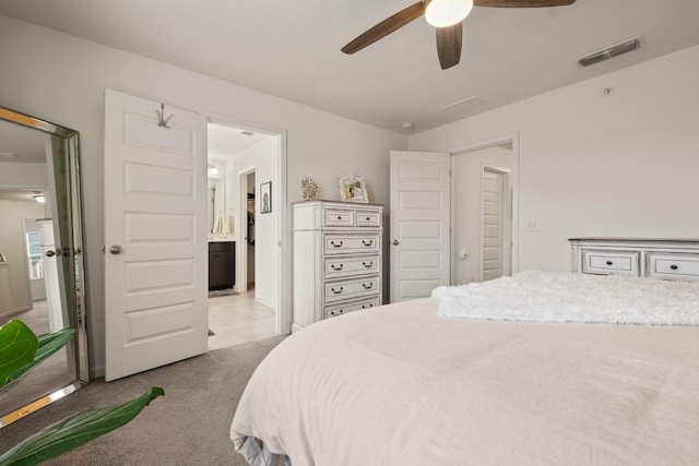 bedroom featuring ensuite bathroom, a ceiling fan, light colored carpet, and visible vents